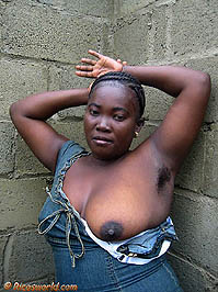 Frany in front of a wall showing hairy armpits and breast